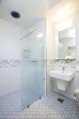 a bathroom with a glass shower and a sink at Hotel California in Seogwipo