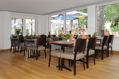 una sala da pranzo con tavoli, sedie e finestre di La Dent-du-Midi Hôtel & Restaurant a Saint-Maurice