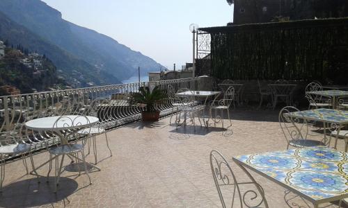 
a patio area with tables, chairs, tables and umbrellas at Villaverde in Positano
