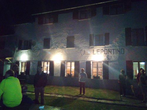 un gruppo di persone che si trovano fuori da un edificio di notte di Albergo Lepontino a Varzo
