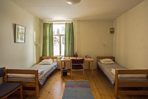 a room with two beds and a table and a window at Valamon Luostari in Uusi-Valamo