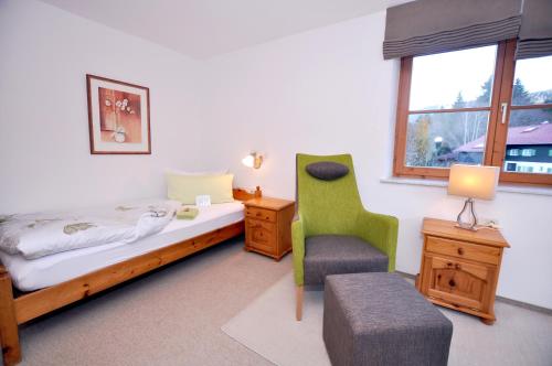 a bedroom with a bed and a chair and a window at Berghüs Schratt - EINFACH ANDERS - Ihr vegetarisches und veganes Biohotel in Oberstaufen