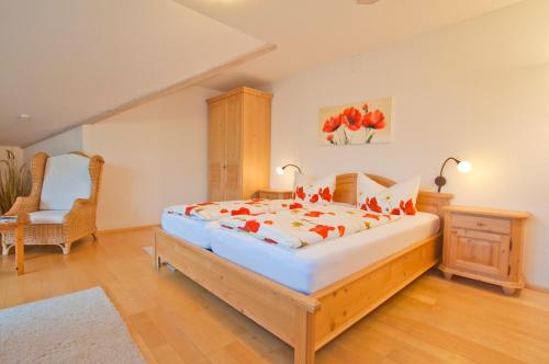 a bedroom with a large bed and a chair at Berghüs Schratt - EINFACH ANDERS - Ihr vegetarisches und veganes Biohotel in Oberstaufen