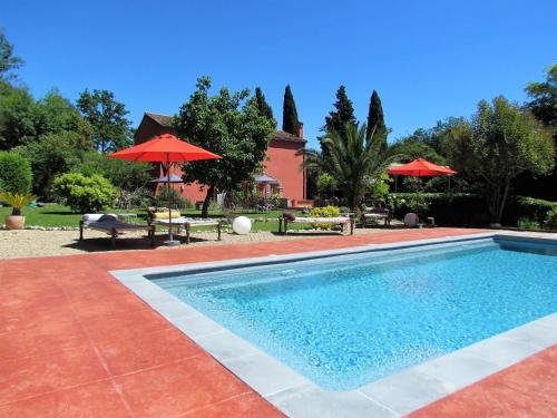 uma piscina com mesas e guarda-sóis e uma casa em Villa Chandra em Biot
