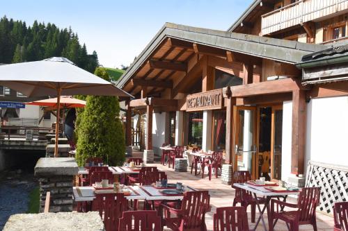 an outdoor restaurant with tables and chairs and an umbrella at Loc'Hotel Alpen Sports in Les Gets