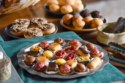 a plate of pastries on a table with plates of donuts at Loc'Hotel Alpen Sports in Les Gets