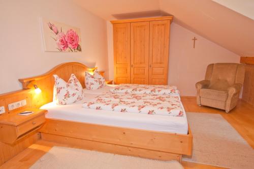 a bedroom with a bed and a chair in it at Berghüs Schratt - EINFACH ANDERS - Ihr vegetarisches und veganes Biohotel in Oberstaufen