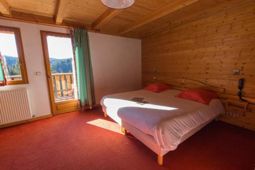 a bedroom with a large bed in a wooden room at Hotel Le Tetras in Notre-Dame-de-Bellecombe