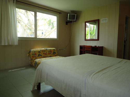 a bedroom with a bed and a chair and a window at Hotel Nitana in Coveñas