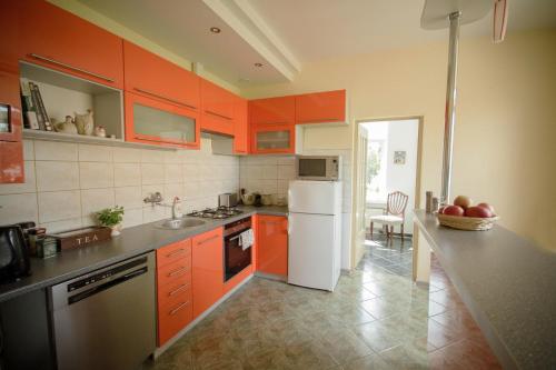kuchnia z pomarańczowymi szafkami i białą lodówką w obiekcie Przyjazne mieszkanie na Starym Miescie w Gnieźnie