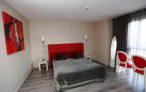 a bedroom with a red bed and a table and chairs at Les Criquets Hôtel & Spa in Blanquefort