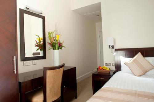 a bedroom with a bed and a mirror and a table at The Villa Kensington in London