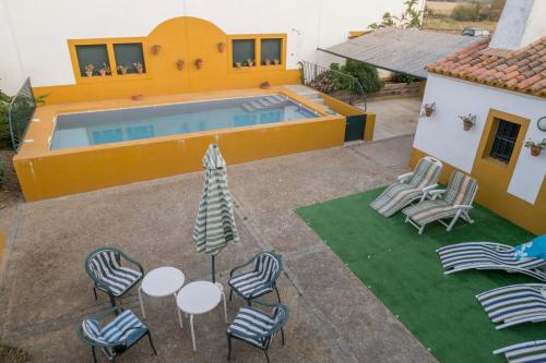 uma vista sobre um pátio com cadeiras e uma piscina em Casa Rural Dehesa de Solana em Herrera de Alcántara