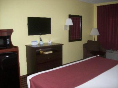 a hotel room with a bed and a flat screen tv at Fairway Inn La Porte in La Porte