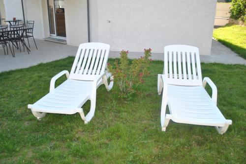two white chairs sitting in the grass in a yard at La Marina in Chassieu