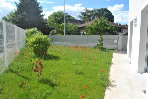 a yard with a fence and a field of flowers at La Marina in Chassieu