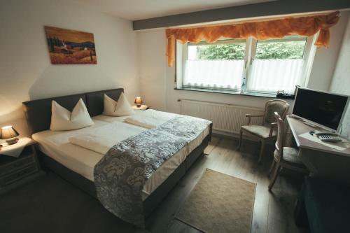 Schlafzimmer mit einem Bett, einem Schreibtisch und einem Computer in der Unterkunft Hotel-Restaurant Walkmühle in Usingen