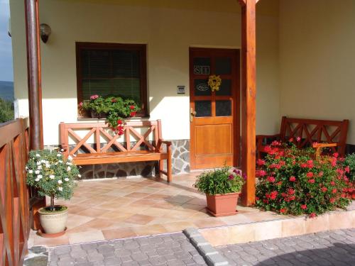 a porch with a bench and flowers in pots at Penzion Martin in Janske Lazne