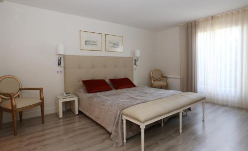ein Schlafzimmer mit einem großen Bett mit zwei roten Kissen in der Unterkunft Les Criquets Hôtel & Spa in Blanquefort