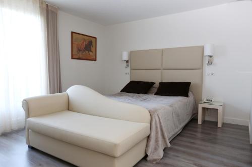 una camera bianca con un letto e un divano bianco di Les Criquets Hôtel & Spa a Blanquefort
