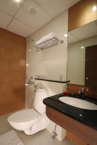 Un baño con inodoro, lavabo y espejo. en Hotel Aquarius, en Vaikom