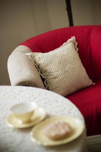 a table with a plate and a pillow on a red couch at Przyjazne mieszkanie na Starym Miescie in Gniezno
