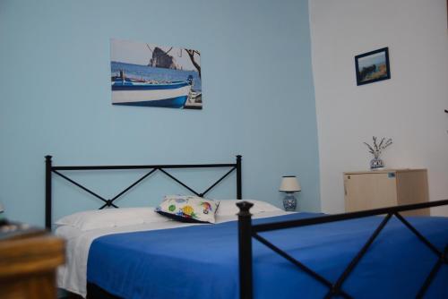 a bedroom with a bed with blue sheets and a picture on the wall at La Sirena in Panarea