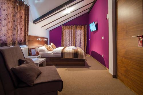 ein Schlafzimmer mit einem Bett und einer lila Wand in der Unterkunft Black Queen Guesthouse in Grabovac