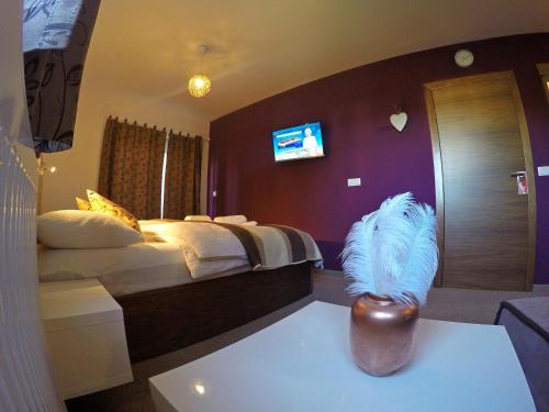 a hotel room with a bed and a vase on a table at Black Queen Guesthouse in Grabovac