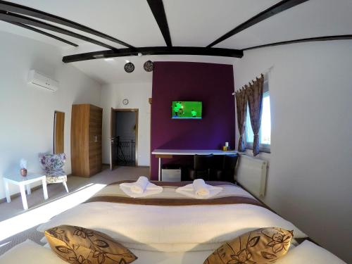 a bedroom with a large bed with a purple wall at Black Queen Guesthouse in Grabovac