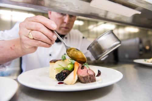 a chef is eating a plate of food with a spoon at Warwick Conferences - Scarman in Coventry