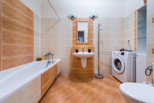 a bathroom with a tub sink and a washing machine at MW Apartamenty - MONTE CASSINO in Sopot