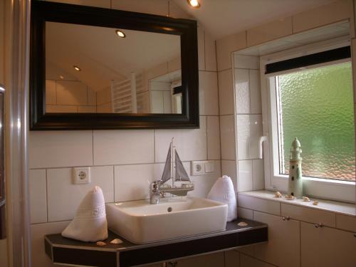 La salle de bains est pourvue d'un lavabo et d'un miroir. dans l'établissement Haus Königsstieg, à Struckum