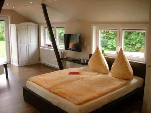 Schlafzimmer mit einem Bett, einem TV und Fenstern in der Unterkunft Haus Königsstieg in Struckum