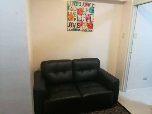 a black leather couch in a living room with a painting at AAA Condominium in Tagaytay