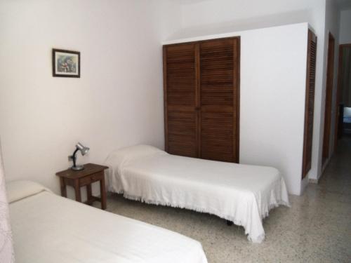 Duas camas num quarto com paredes brancas e uma mesa em Apartamentos Isa em Tazacorte