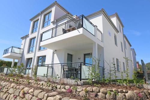 een wit huis met balkons en een stenen muur bij Villa Anni - Wohnung 3 mit Terrasse in Göhren