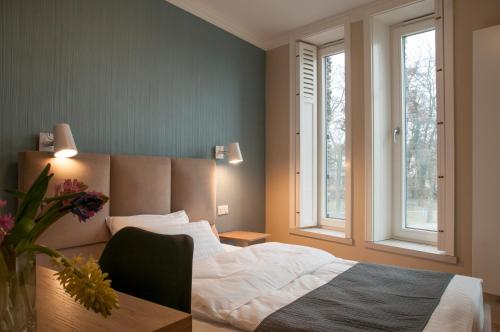 a bedroom with a bed and a desk and two windows at Baltica Residence in Sopot