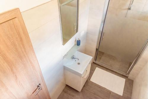 uma casa de banho branca com um lavatório e um chuveiro em Nad Šťastným sklepem em Valtice