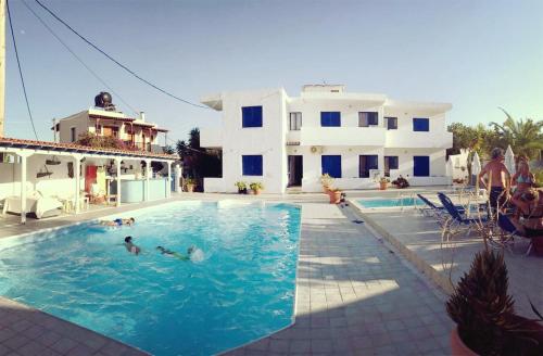 eine Gruppe von Menschen in einem Schwimmbad neben einem Haus in der Unterkunft Helios Hotel in Agia Marina