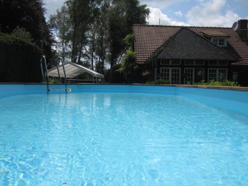 a large blue swimming pool in front of a house at La Croix du Reh in Châteauneuf-la-Forêt