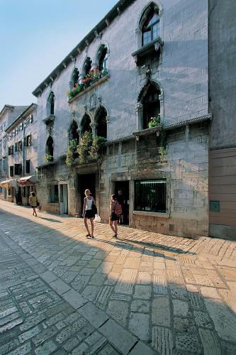 two people walking down a street in front of a building at Studio Apartment Sofia - Poreč Old Town Quiet Oasis with FREE parking in Poreč