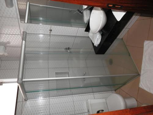 a bathroom with a glass shower with a toilet and a sink at Hotel Lider - Catanduva in Catanduva
