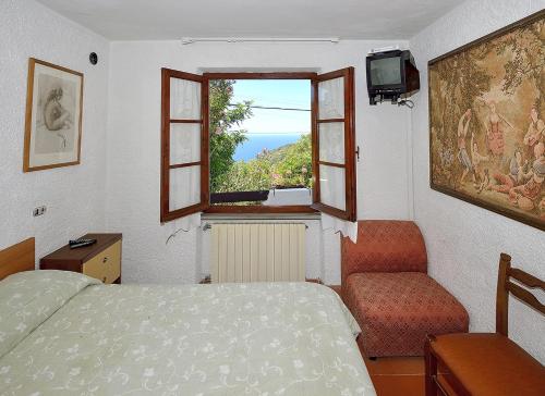 1 dormitorio con cama, ventana y silla en Appartamento vista mare en La Guardia