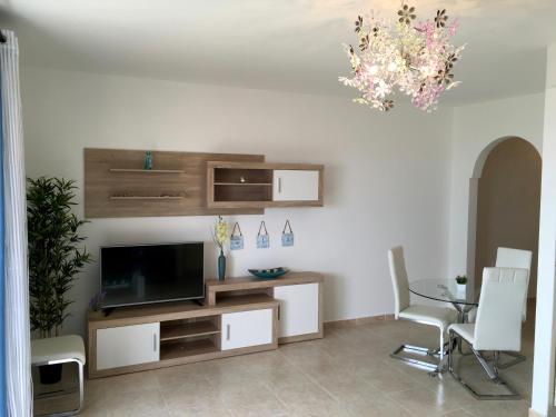 a living room with a television and a table and chairs at El Granillo G-96 in Costa Calma