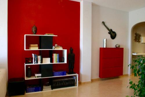 una habitación con una pared roja y un estante de libros en Apartamento Can Xavi, en Santa Bárbara