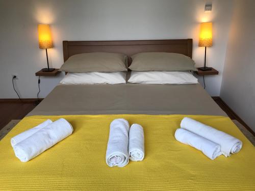 a bed with three rolled towels on a yellow blanket at Apartmani Marija Klimno B in Klimno