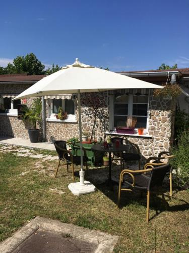 a table and chairs under an umbrella in a yard at Aerotel Versailles Saint Cyr - L'étape du Silence in Saint-Cyr-lʼÉcole