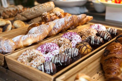 a display case filled with lots of different types of donuts at Winter Garden Hotel Bergamo Airport in Grassobbio