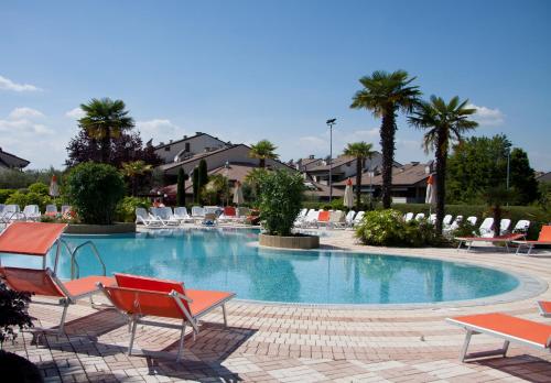 una piscina con sedie e palme in un resort di Lauri & Faggi a Desenzano del Garda